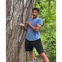 sam hopson standing next to a tree trunk